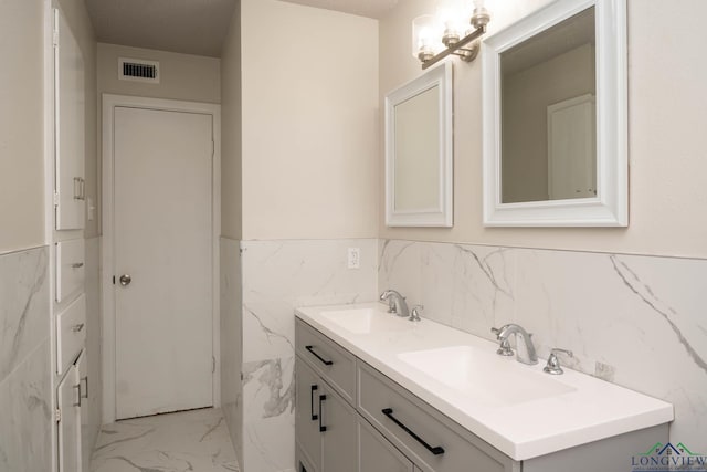 full bathroom featuring marble finish floor, visible vents, a sink, and double vanity