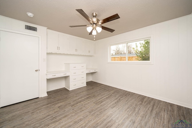 interior space featuring dark wood-style floors, visible vents, a textured ceiling, and built in study area