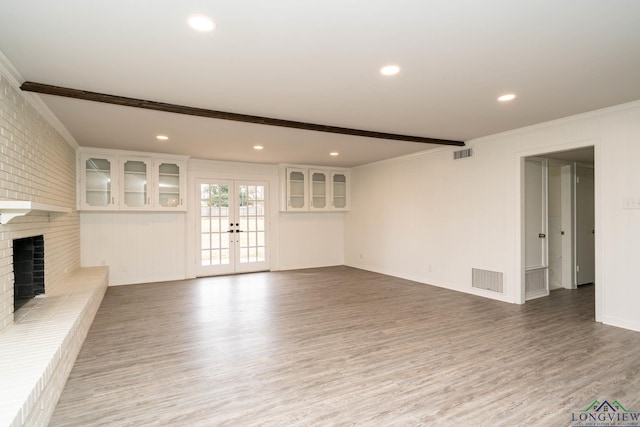 unfurnished living room with beam ceiling, visible vents, a fireplace, and wood finished floors