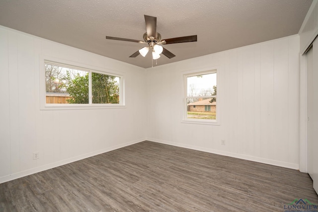 spare room featuring dark wood-style floors, ceiling fan, baseboards, and a textured ceiling