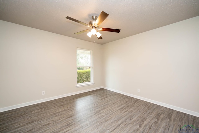 spare room featuring dark wood-style flooring, a textured ceiling, and baseboards