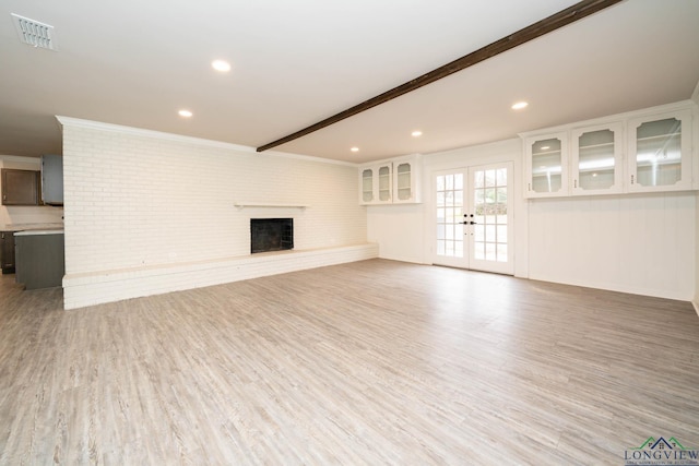 unfurnished living room with french doors, a fireplace, visible vents, light wood-style flooring, and beamed ceiling