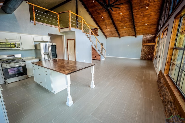 kitchen with white cabinets, a kitchen island, stainless steel appliances, and high vaulted ceiling