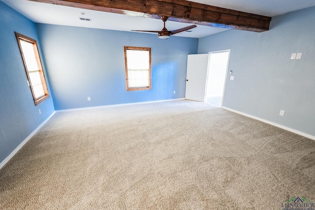 carpeted empty room featuring beamed ceiling, ceiling fan, and plenty of natural light