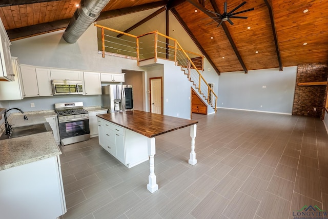 kitchen with wooden counters, appliances with stainless steel finishes, sink, a center island, and white cabinetry