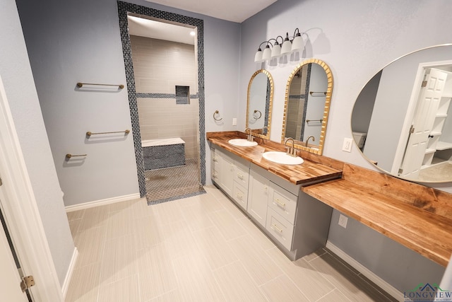 bathroom with a tile shower, tile patterned floors, and vanity