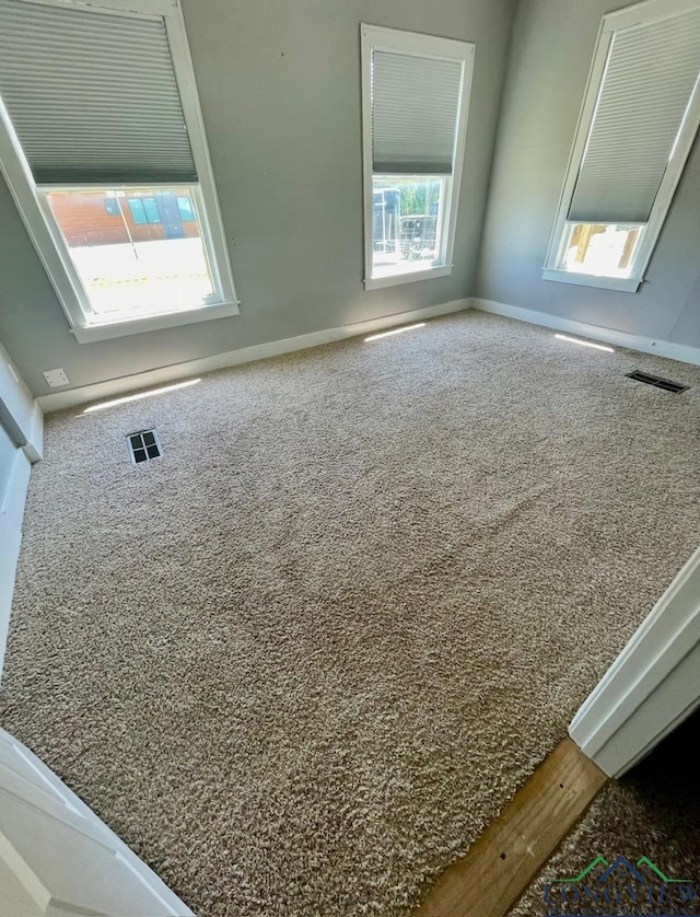 carpeted spare room with baseboards and visible vents