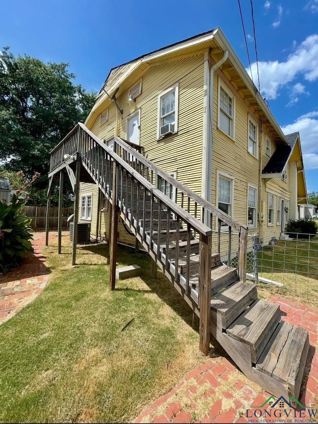 back of property featuring fence, a wooden deck, a yard, and stairs