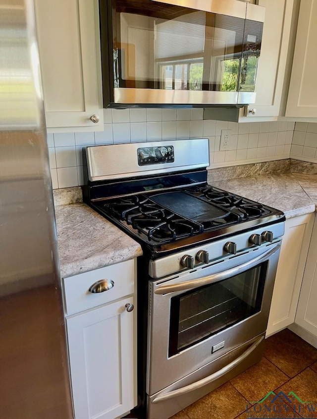 kitchen featuring light countertops, white cabinets, appliances with stainless steel finishes, and tasteful backsplash