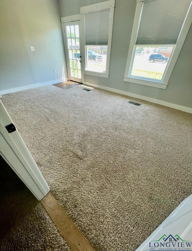carpeted spare room featuring visible vents and baseboards