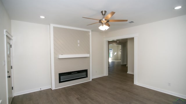 unfurnished living room with a large fireplace, dark hardwood / wood-style floors, and ceiling fan