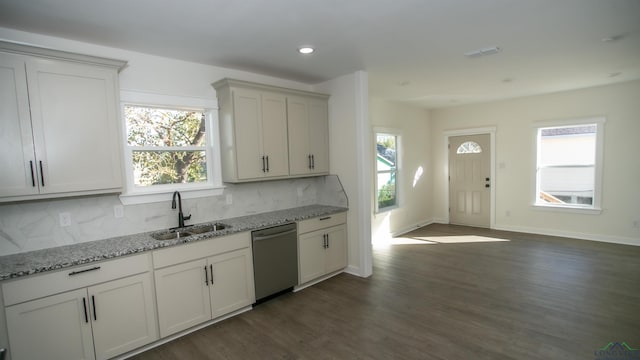 kitchen with dishwasher, backsplash, light stone countertops, and sink