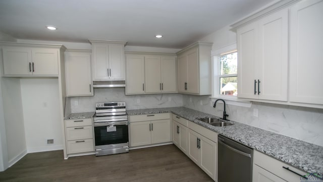 kitchen with backsplash, stainless steel appliances, light stone counters, and sink