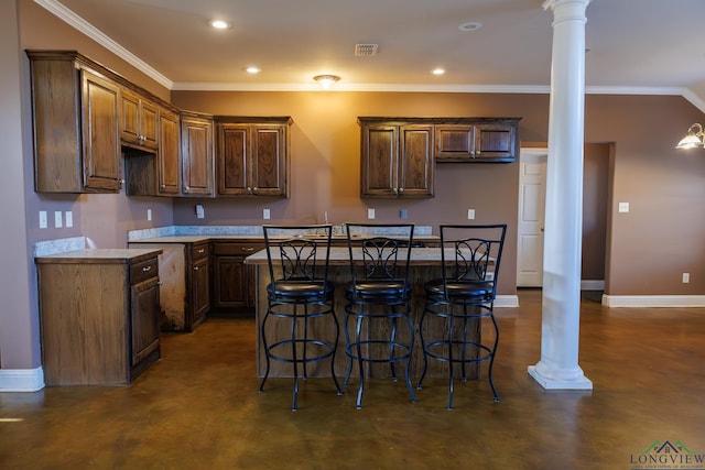 kitchen with crown molding, a breakfast bar, a kitchen island, and ornate columns