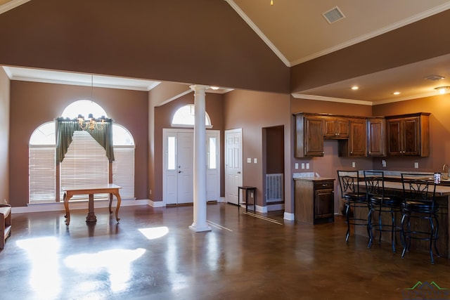 dining space with high vaulted ceiling, ornamental molding, ornate columns, and an inviting chandelier