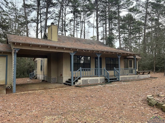 view of front of house with a carport, a porch, and a chimney