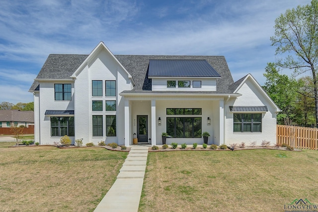 modern inspired farmhouse featuring roof with shingles, fence, a front lawn, and brick siding