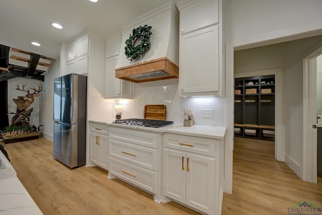 kitchen with white cabinets, recessed lighting, custom exhaust hood, appliances with stainless steel finishes, and light wood finished floors