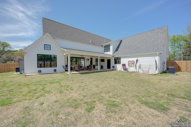 back of house featuring roof with shingles, a patio, a fenced backyard, and a lawn