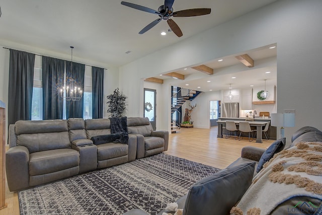 living room featuring light wood-type flooring, ceiling fan with notable chandelier, beamed ceiling, and recessed lighting