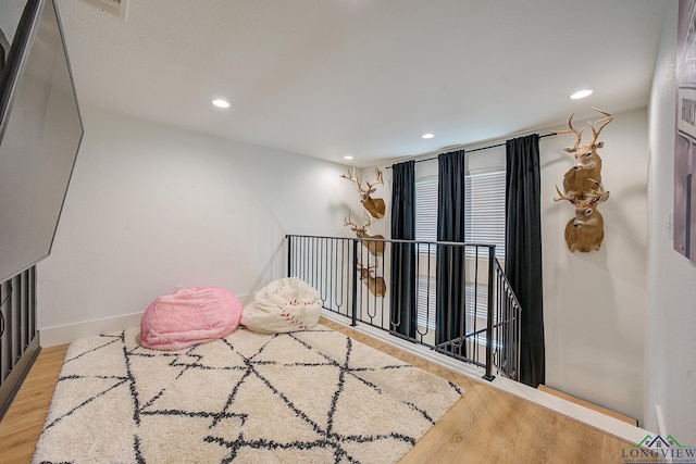 interior space with wood finished floors, an upstairs landing, and recessed lighting