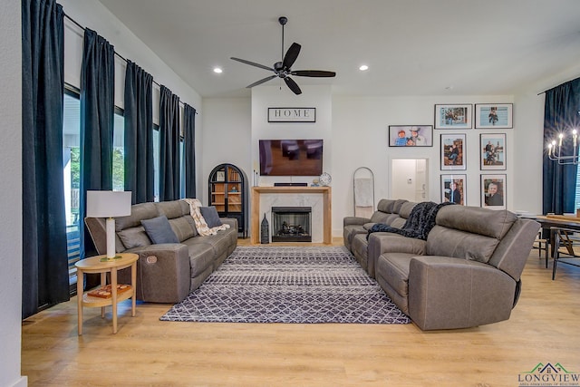 living area with ceiling fan, recessed lighting, a premium fireplace, and wood finished floors