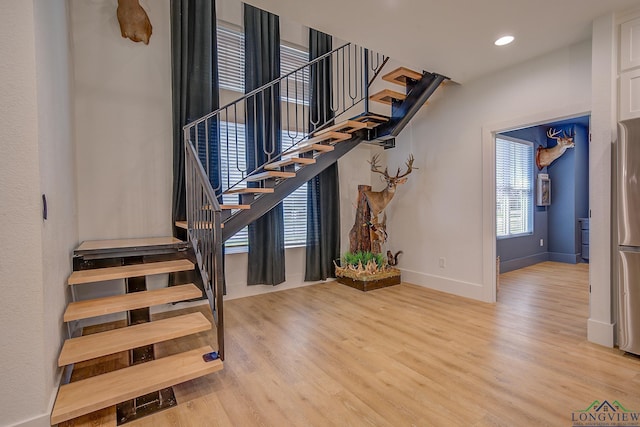 stairway featuring wood finished floors, baseboards, and recessed lighting