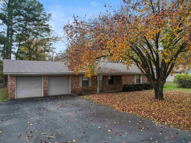 ranch-style home with a garage, aphalt driveway, a shingled roof, and brick siding