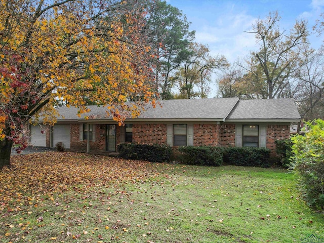 ranch-style home featuring roof with shingles, brick siding, a front lawn, and an attached garage