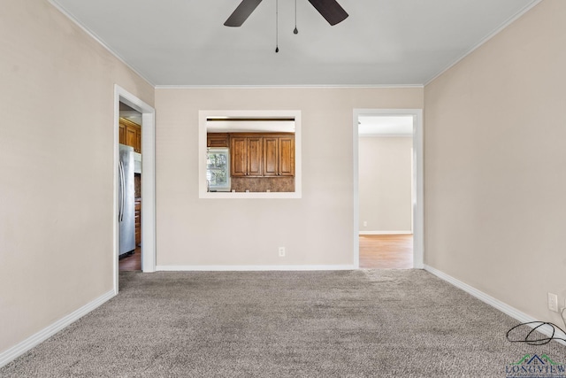 spare room featuring carpet floors, ornamental molding, and a ceiling fan