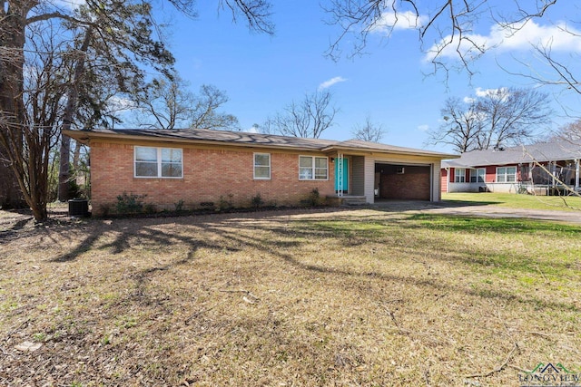 single story home with brick siding, a front lawn, central AC, driveway, and an attached garage