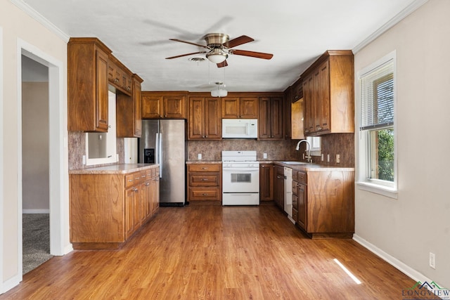 kitchen with white appliances, a ceiling fan, light wood finished floors, a sink, and decorative backsplash