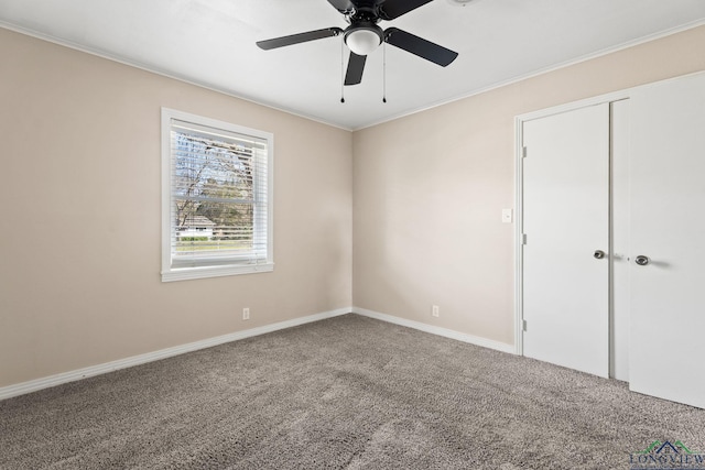 unfurnished bedroom featuring a closet, a ceiling fan, crown molding, and carpet