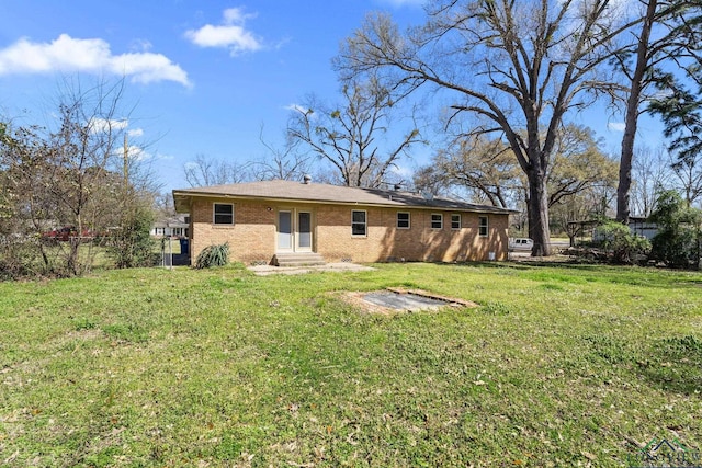 back of property featuring brick siding, a lawn, and entry steps