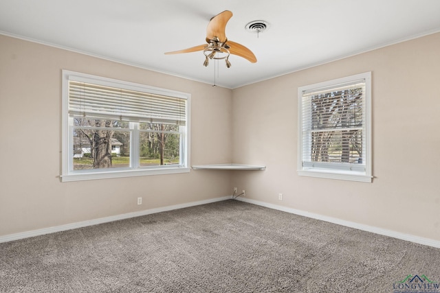 carpeted spare room with visible vents, baseboards, ceiling fan, and crown molding