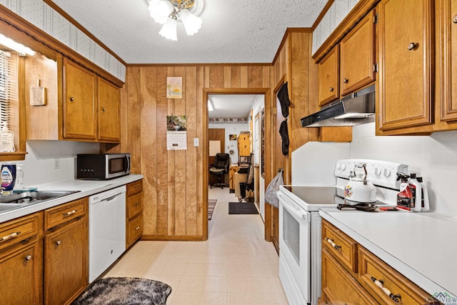 kitchen featuring ceiling fan, wood walls, a textured ceiling, white appliances, and ornamental molding