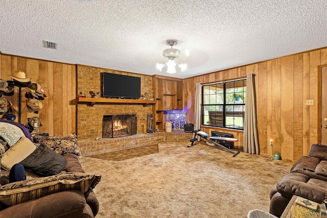 living room featuring carpet flooring, wood walls, a fireplace, and a textured ceiling