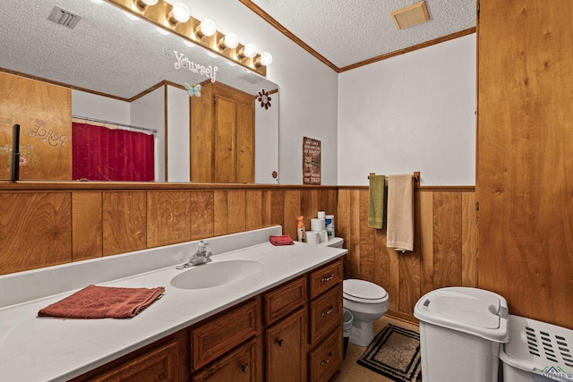 bathroom with vanity, a textured ceiling, wooden walls, crown molding, and toilet