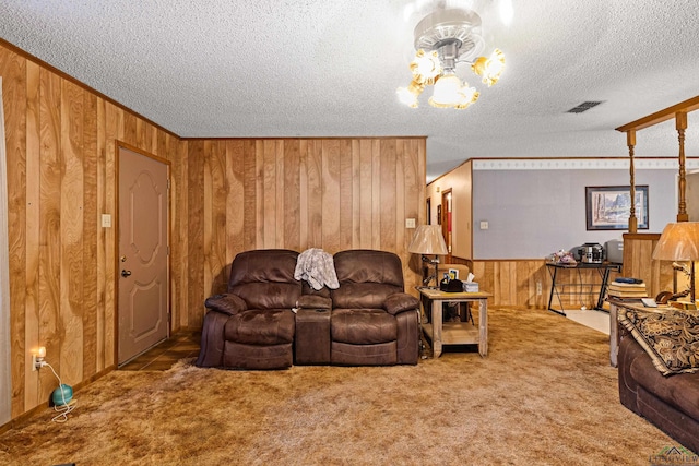 carpeted living room with wooden walls, crown molding, a textured ceiling, and a notable chandelier