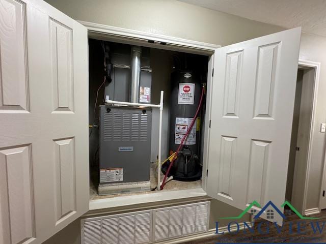 utility room featuring gas water heater and heating unit