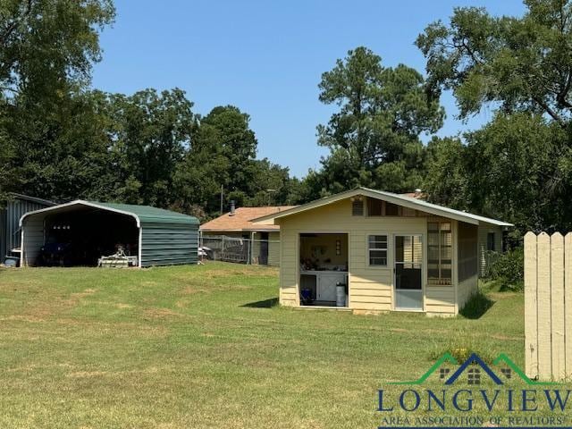 back of property with a carport and a yard