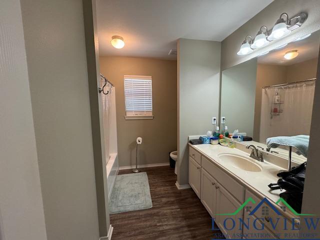 full bathroom with hardwood / wood-style floors, vanity, toilet, and shower / bathtub combination with curtain