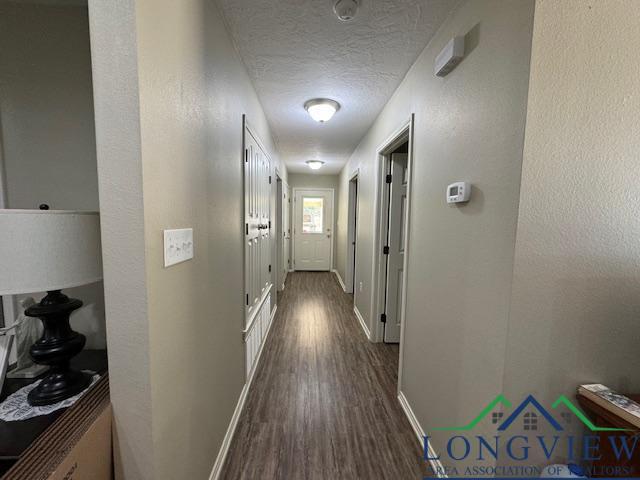 hall featuring dark wood-type flooring and a textured ceiling