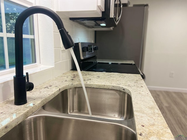 room details with decorative backsplash, electric range, light stone counters, and hardwood / wood-style flooring