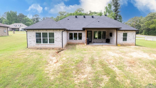 rear view of property with fence, a yard, a patio area, brick siding, and roof with shingles