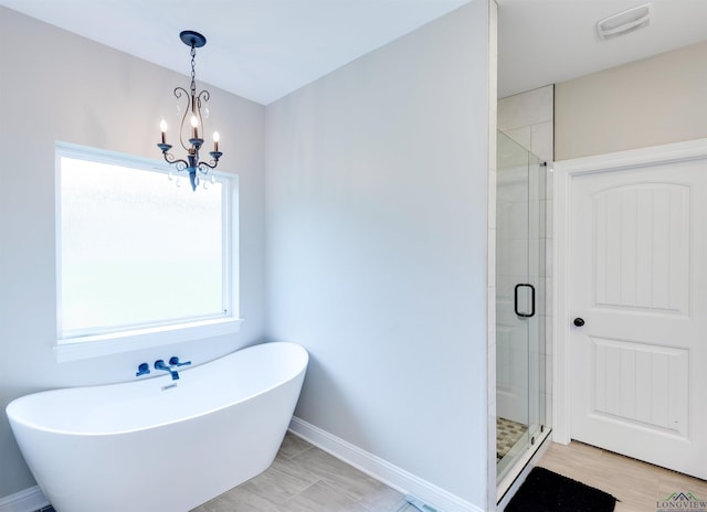 bathroom with a freestanding bath, a stall shower, baseboards, visible vents, and a notable chandelier