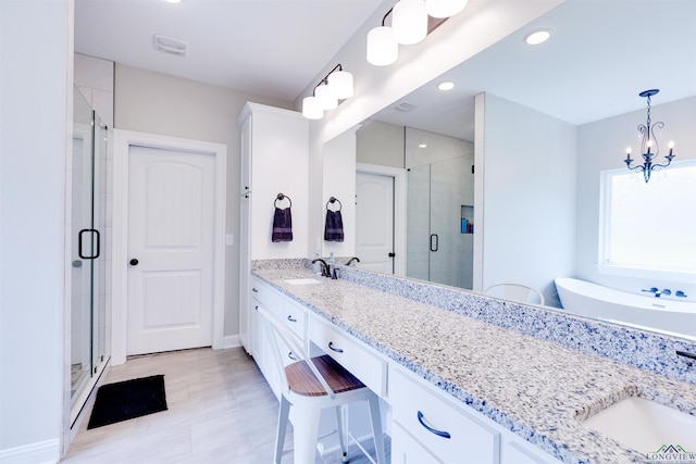 full bathroom with a notable chandelier, a sink, double vanity, and a stall shower