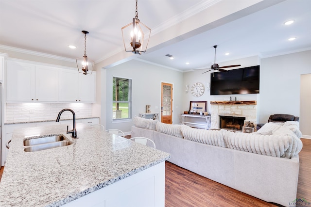 living room with recessed lighting, wood finished floors, ceiling fan, a fireplace, and ornamental molding
