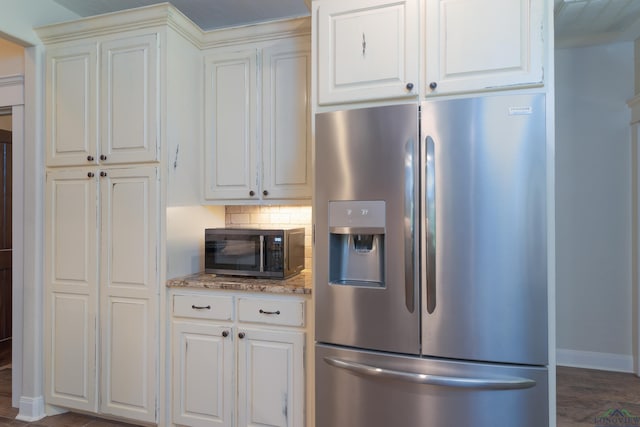 kitchen featuring white cabinetry, stainless steel fridge, and light stone counters