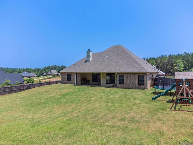 rear view of property with a playground and a yard